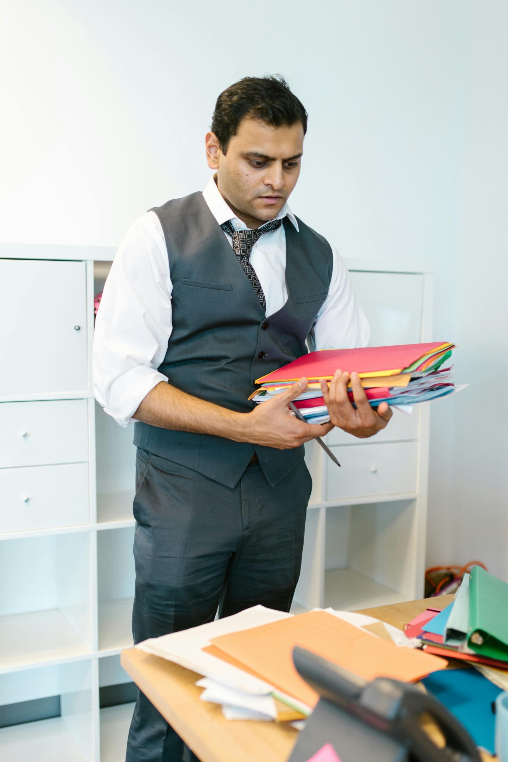 A focused businessman organizing folders in a modern office setting.